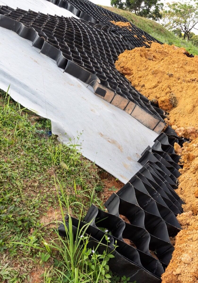 Close-up on slope erosion control materials with grids, sheets and earth on steep slope